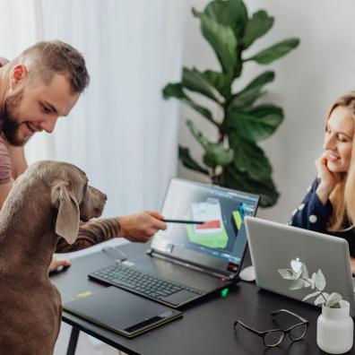 Woman and a Man Presenting Image on a Laptop Screen to a Dog